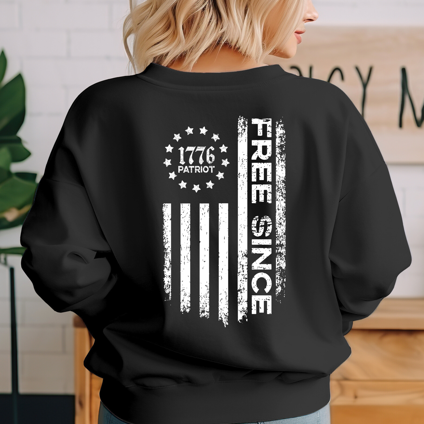 Person wearing a black sweatshirt with white text and design, standing indoors.