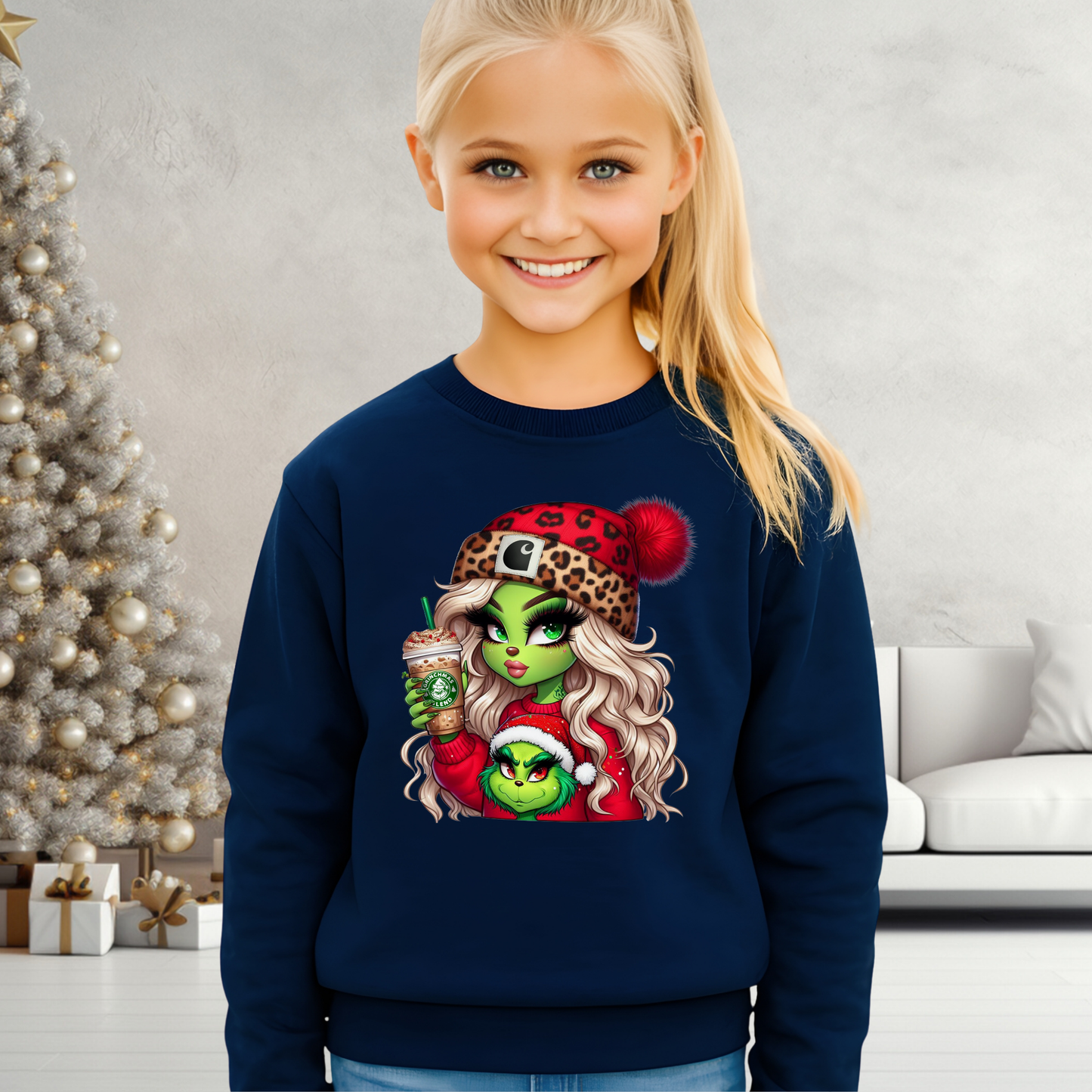 Child wearing a navy blue sweatshirt with a festive design, standing in a room decorated for Christmas.