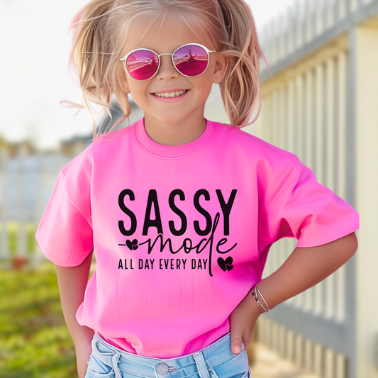 oung girl wearing a navy bright Pink "Sassy Mode – All Day Every Day" graphic t-shirt, smiling confidently outdoors