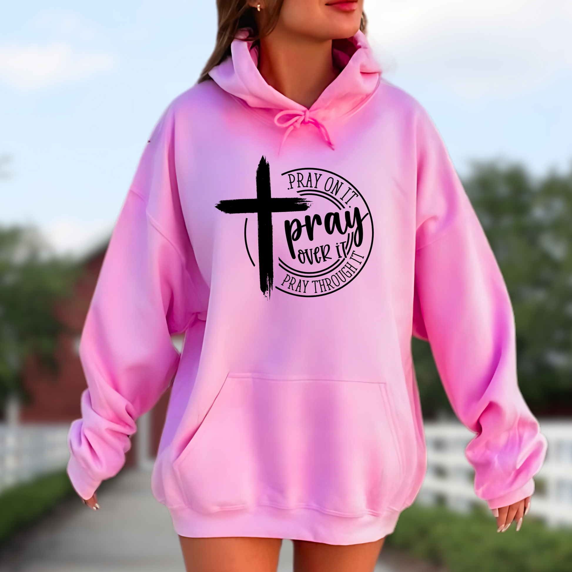 Woman wearing a bright pink hoodie with a motivational message and cross symbol.