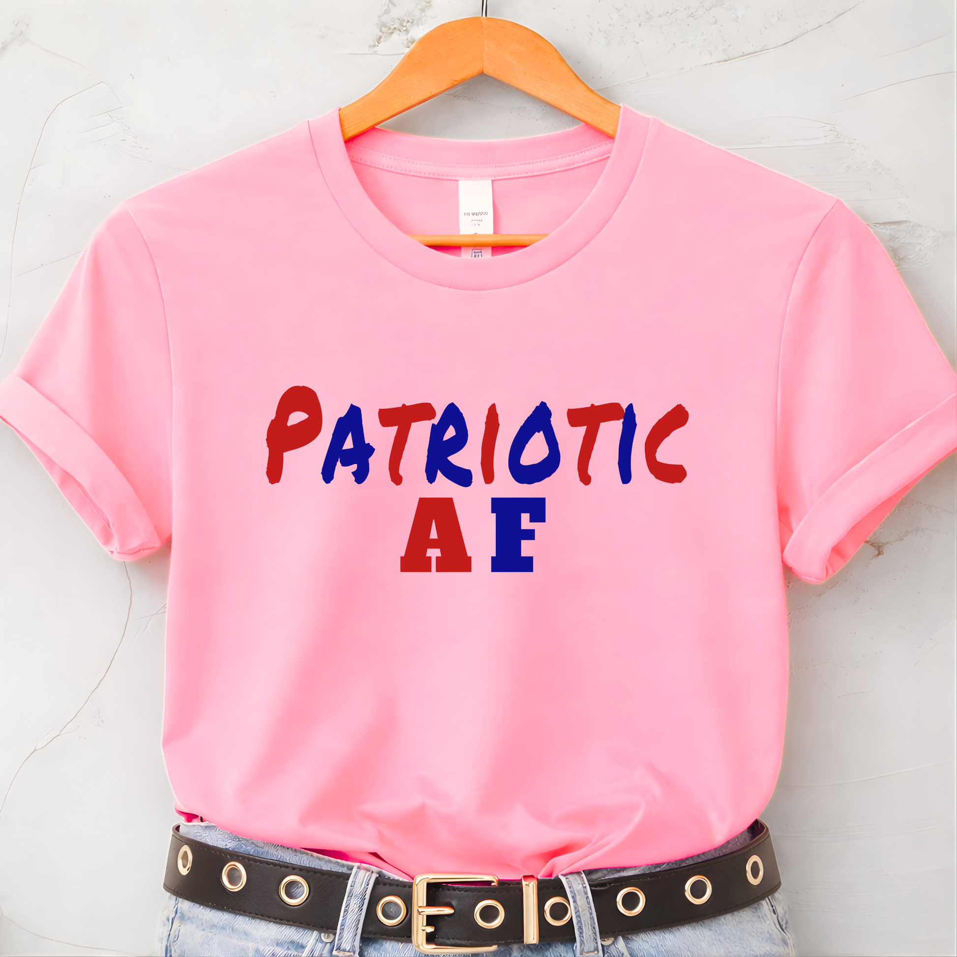 Pink patriotic AF graphic t-shirt hanging on hanger flat lay