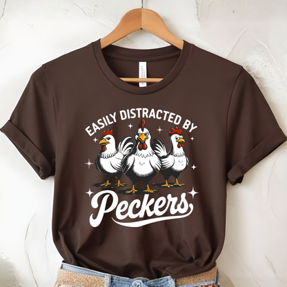 Brown t-shirt with chicken graphic and text on a hanger against a white wall.