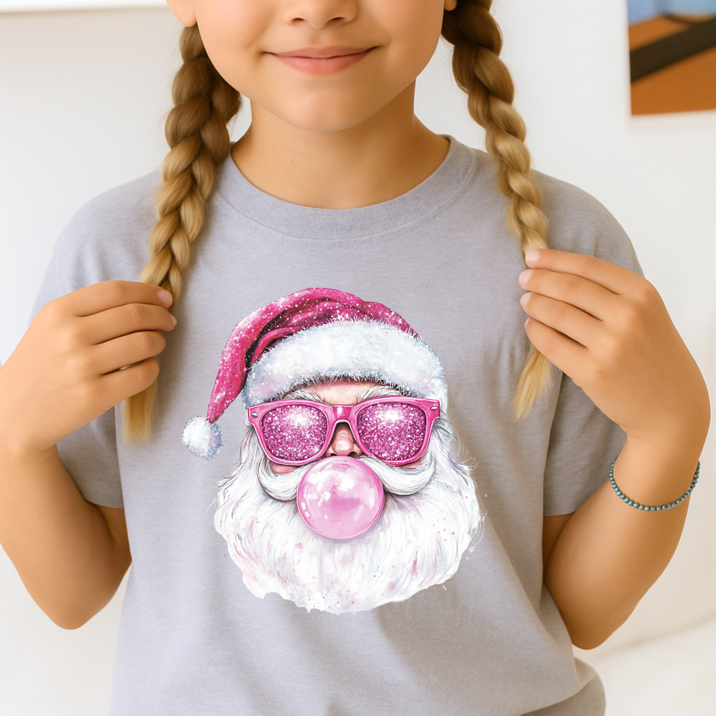 Child wearing a t-shirt with a colorful Santa Claus design, including a pink hat and sunglasses.
