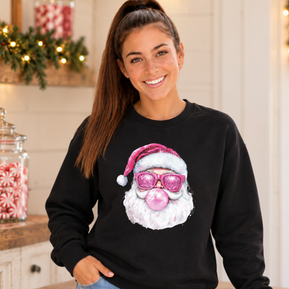 Woman wearing a black Bubblegum Santa crewneck sweatshirt in a simple Christmas kitchen with peppermint candy jars and greenery