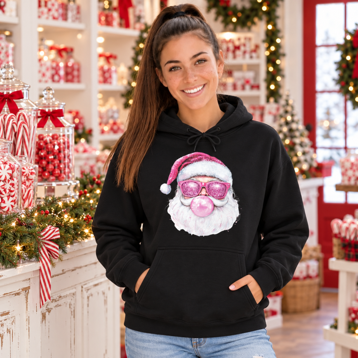 Woman wearing a black Bubblegum Santa hoodie in a Christmas candy shop with candy canes, greenery, and lights