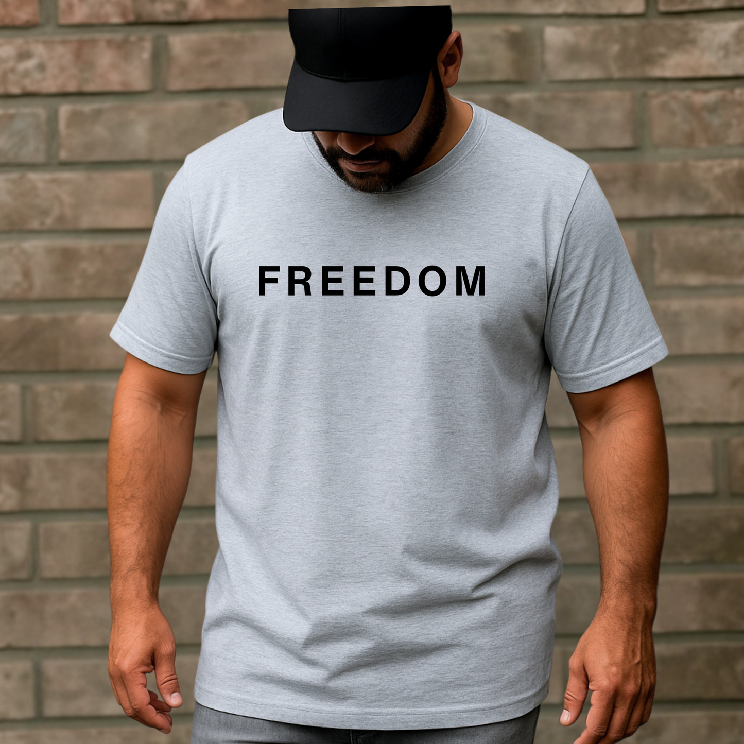 Man wearing a gray t-shirt with 'FREEDOM' printed on it against a brick wall.