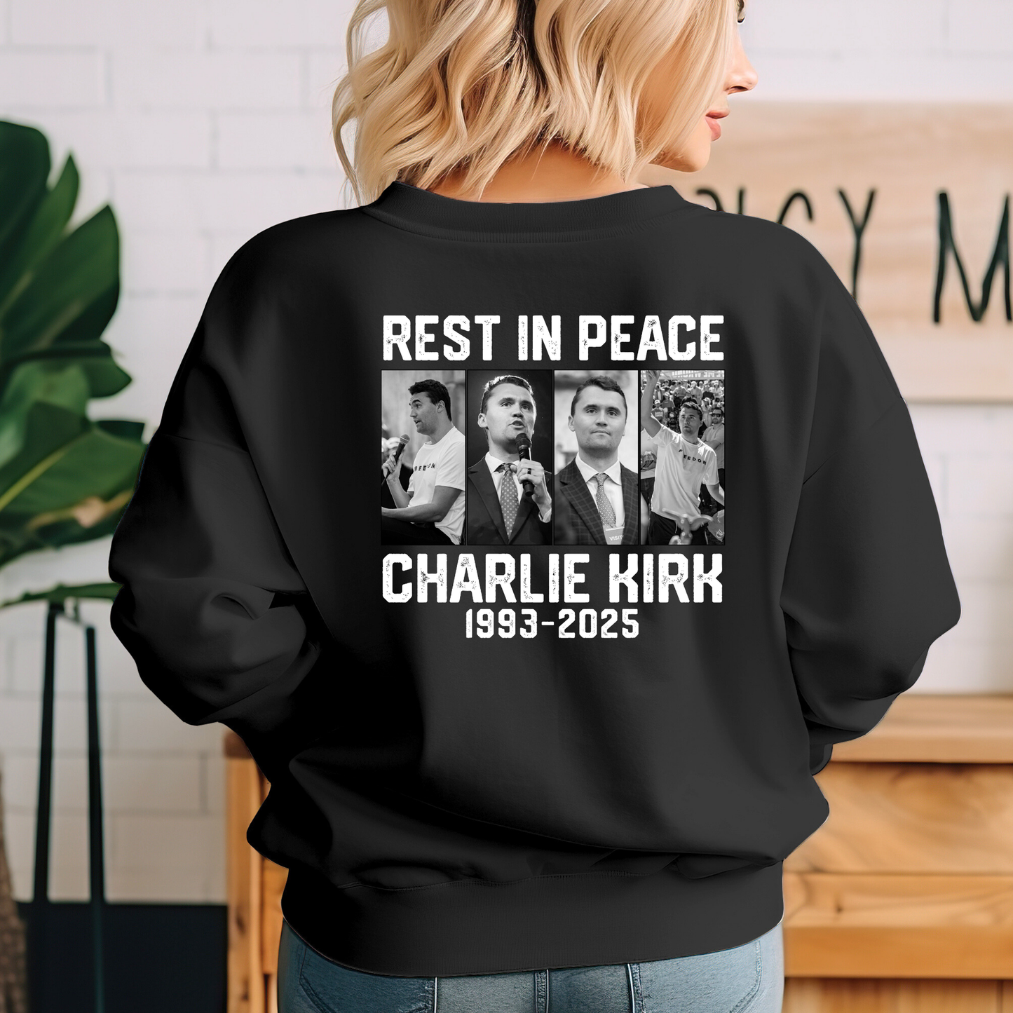 Black sweatshirt with 'Rest in Peace Charlie Kirk 1993-2025' text and images on the back, worn by a person.