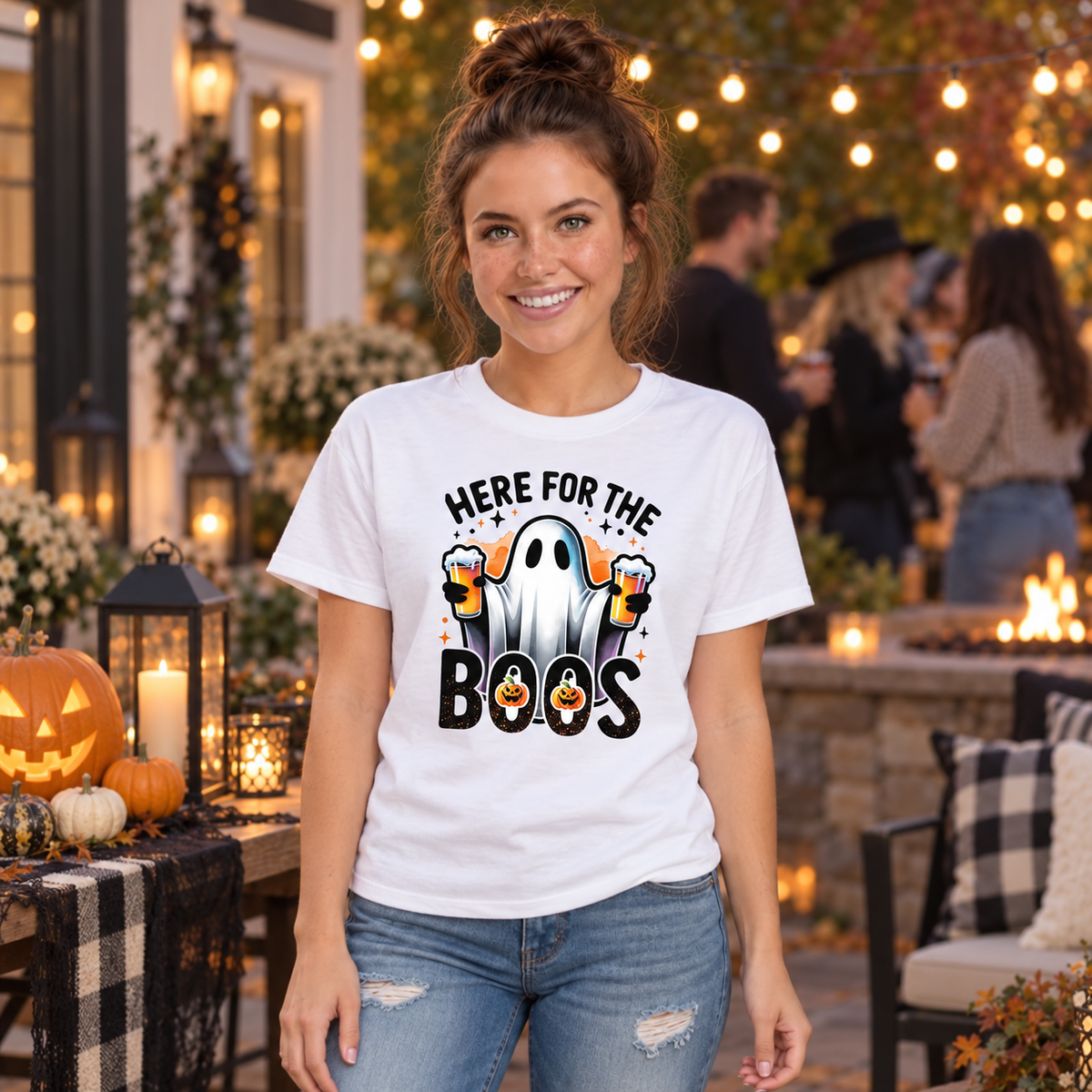 Woman wearing a white T-shirt with a beer-holding ghost and Here For The Boos design at an outdoor Halloween party.