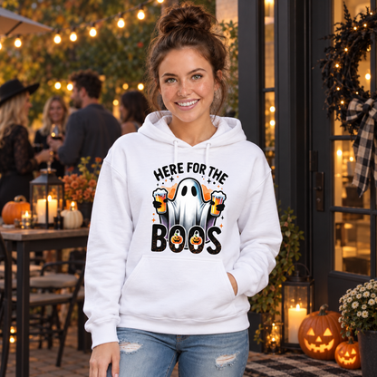 Woman wearing a white hoodie featuring the Here For The Boos beer ghost design at an outdoor Halloween party.