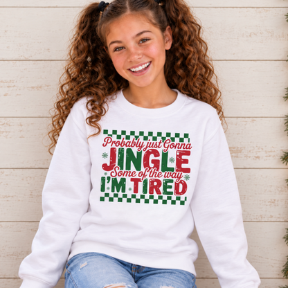 Girl wearing a white youth sweatshirt with red and green Probably Just Gonna Jingle Some of the Way I'm Tired Christmas design by a café window