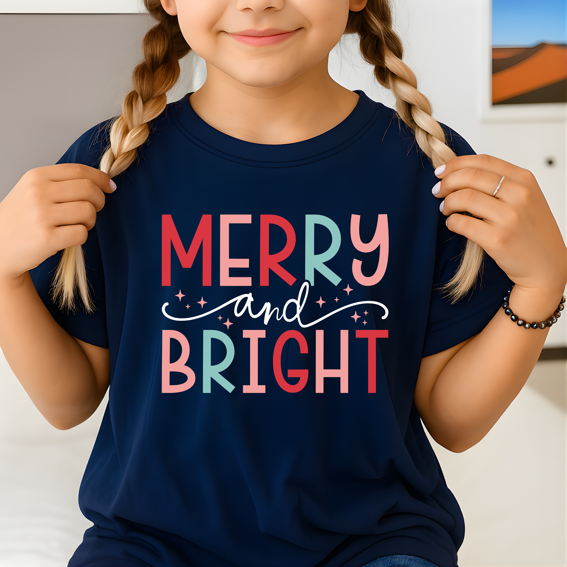 Child wearing a navy blue t-shirt with 'Merry and Bright' text in colorful letters.