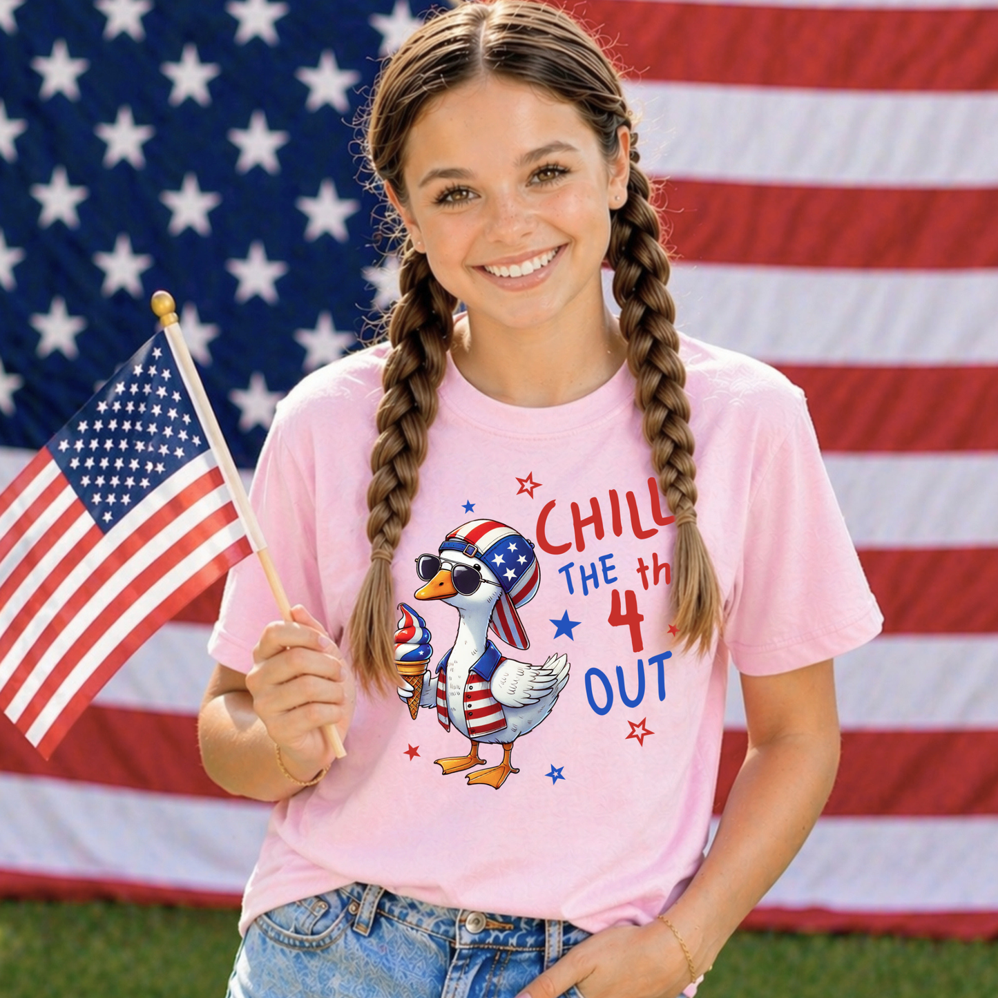 Girl wearing a pink t-shirt with a patriotic design, holding an American flag in front of an American flag background.