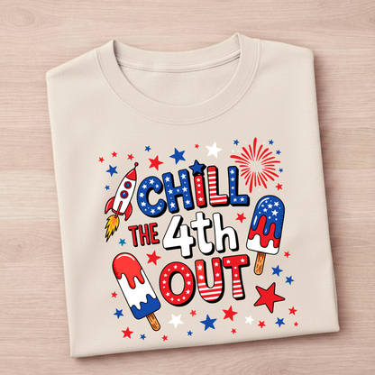 Beige t-shirt with 4th of July-themed graphics and text on a wooden surface