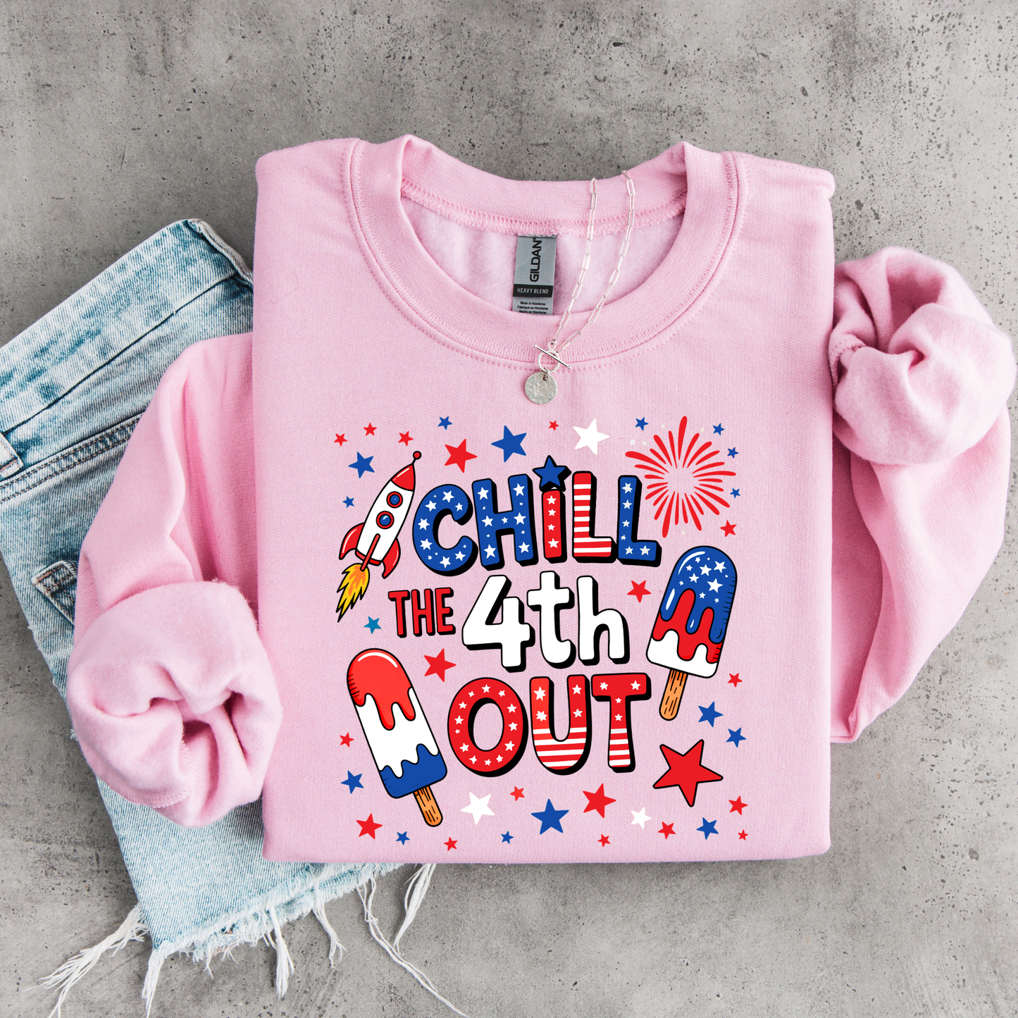 Pink sweatshirt with 4th of July-themed design on a concrete surface