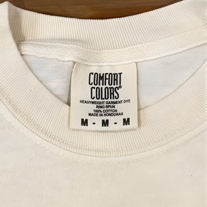 Close-up of a white garment with a 'Comfort Colors' label on a wooden surface.