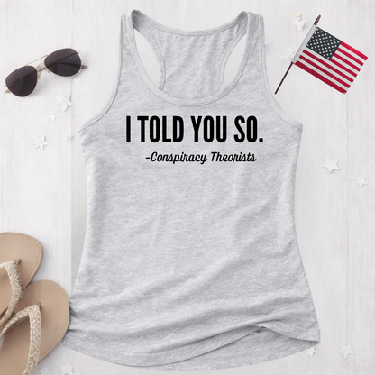 Gray tank top with 'I Told You So. - Conspiracy Theorists' text, sunglasses, and American flag on a white background