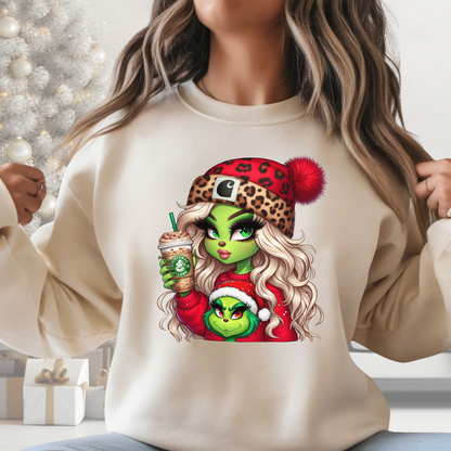 Person wearing a beige sweatshirt with a festive character design, including a coffee drink, in a decorated room.