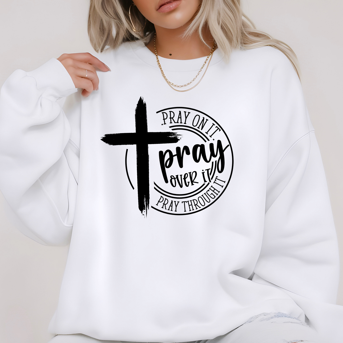 White sweatshirt with black cross and text design worn by a person.