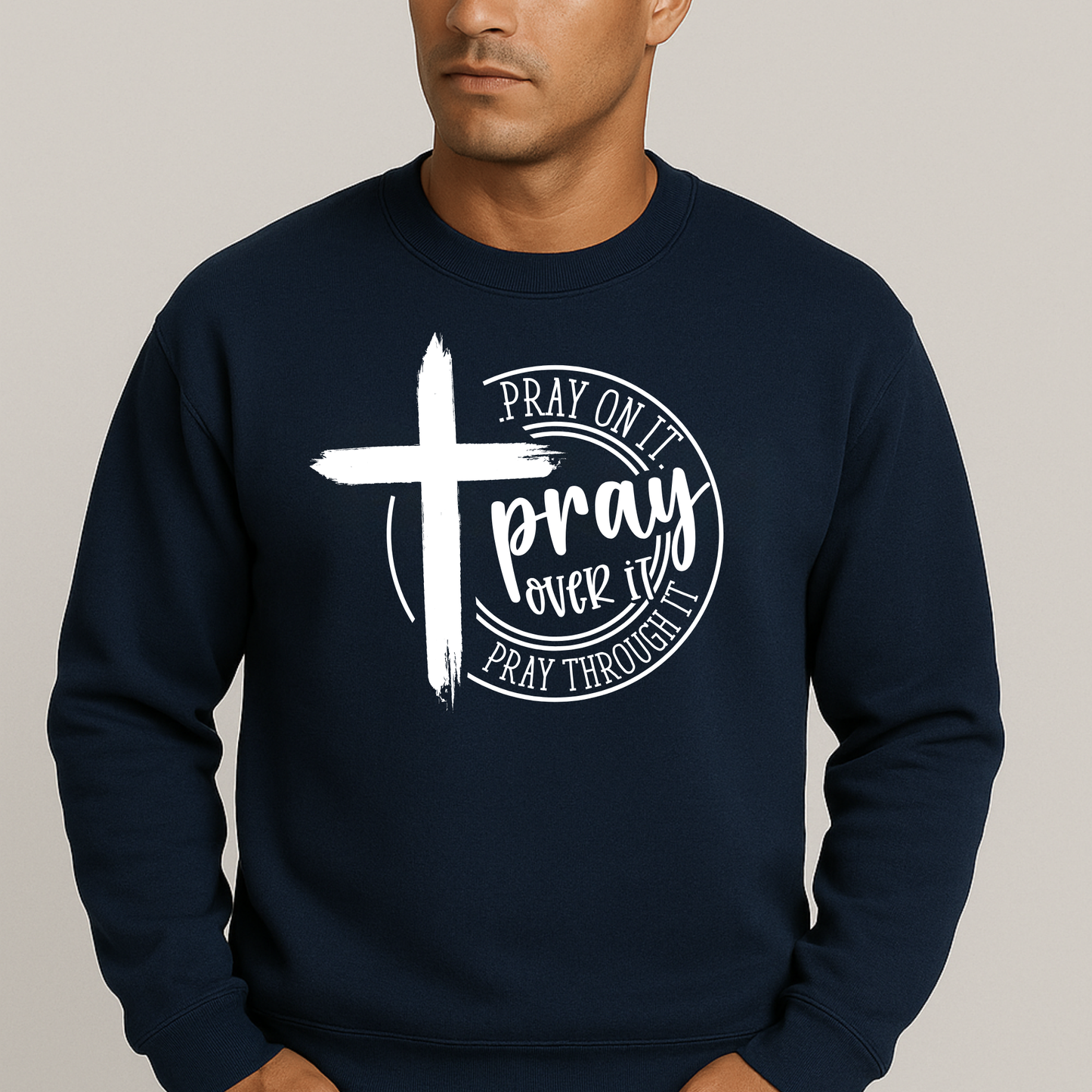 Man wearing an navy sweatshirt with a bold white cross and text: "Pray On It, Pray Over It, Pray Through It"