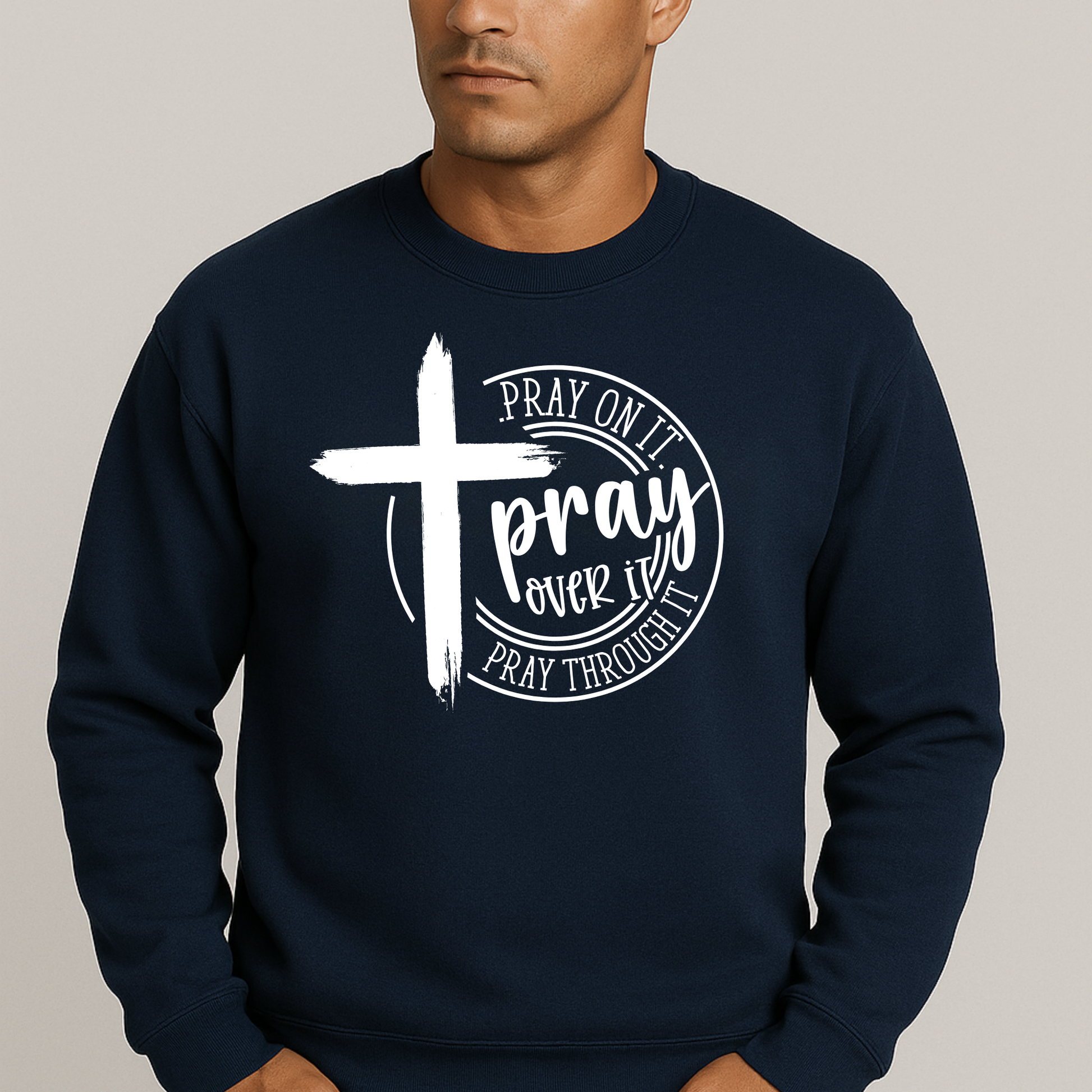Man wearing an navy sweatshirt with a bold white cross and text: "Pray On It, Pray Over It, Pray Through It"