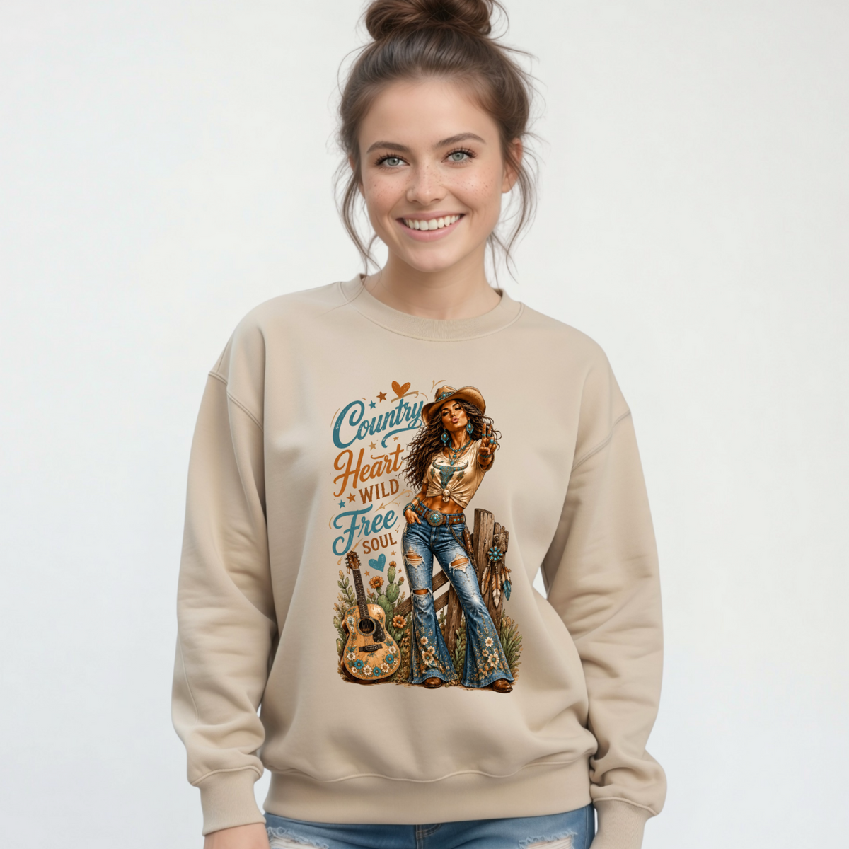 Woman modeling a sand crewneck sweatshirt with the Country Heart Wild Free Soul western cowgirl graphic on a clean studio background.