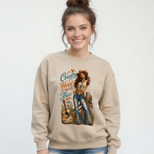 Woman modeling a sand crewneck sweatshirt with the Country Heart Wild Free Soul western cowgirl graphic on a clean studio background.