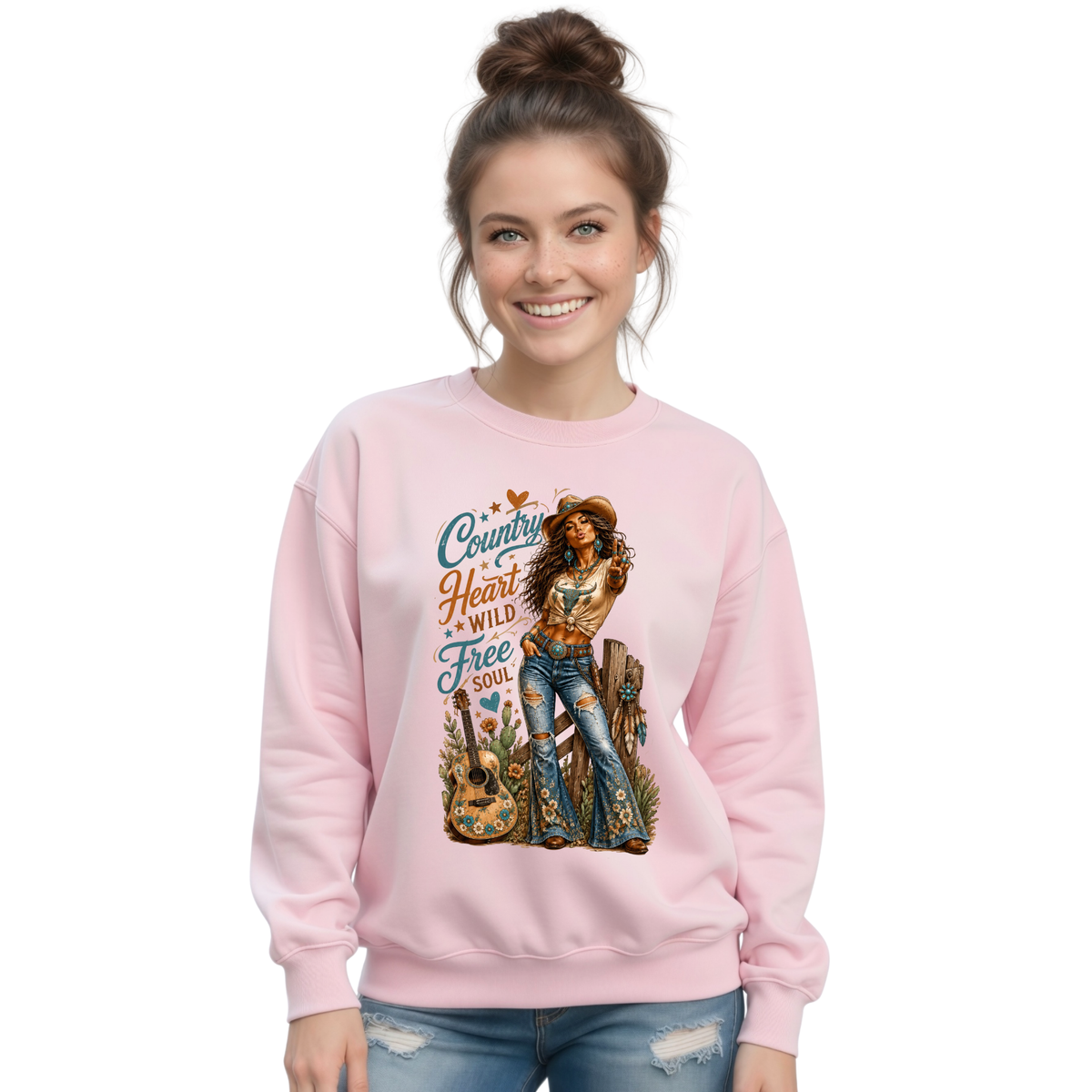 Woman modeling a light pink crewneck sweatshirt with the Country Heart Wild Free Soul cowgirl artwork on a bright white background.