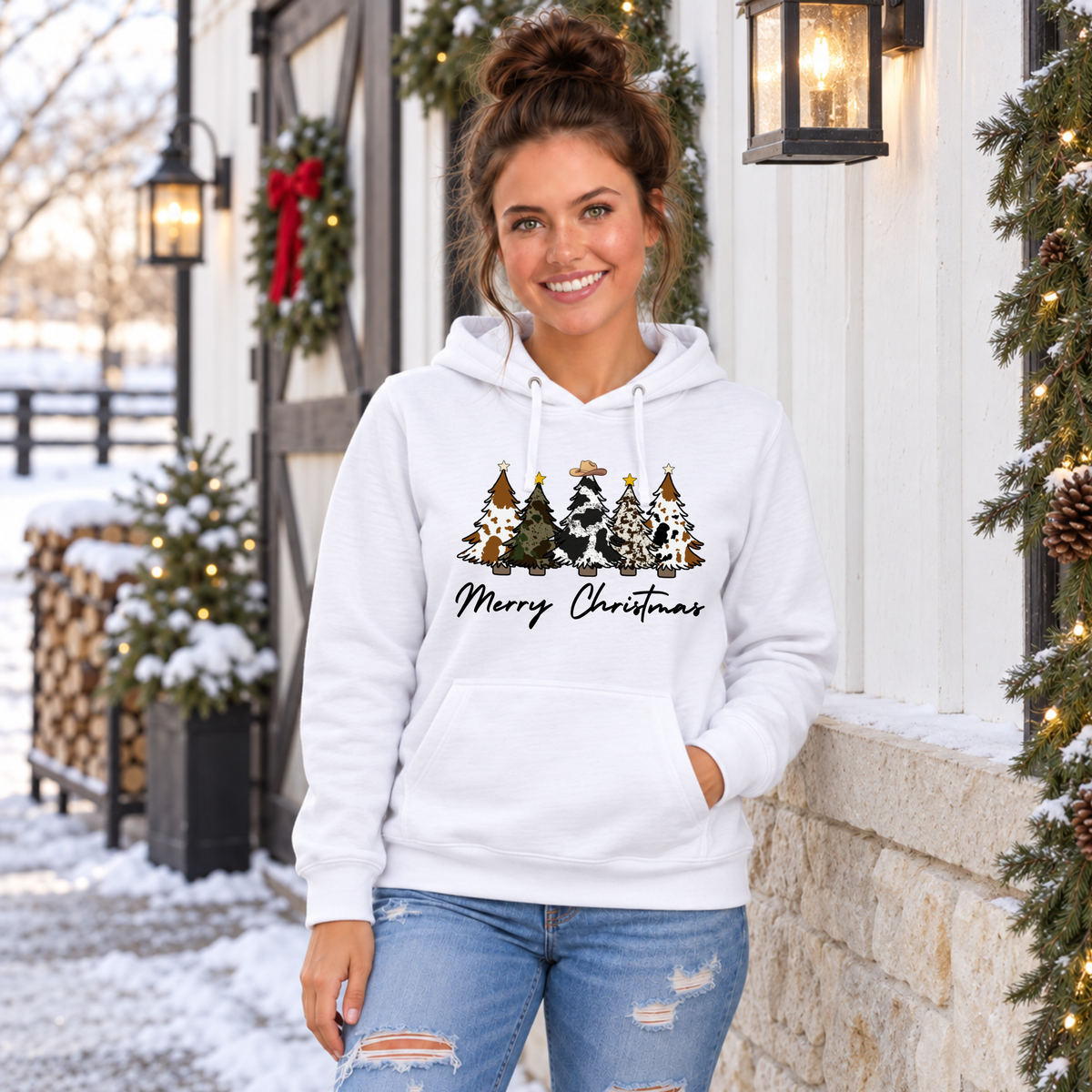 Woman wearing a white Merry Christmas cow print trees hoodie outside a snowy holiday storefront.