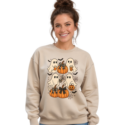 A woman wearing a beige crewneck sweatshirt with a Halloween graphic of cartoon ghosts, pumpkins, bats, and a spider, paired with distressed blue jeans, against a plain white background.