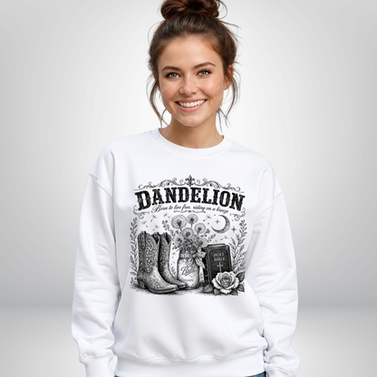 Woman wearing a white Dandelion crewneck sweatshirt with cowboy boots, dandelion-filled mason jar, Holy Bible, rose, and crescent moon graphic on a white background