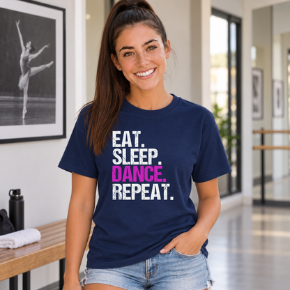 Woman wearing a navy Eat Sleep Dance Repeat T-shirt near a dance studio bench and dancer portrait.