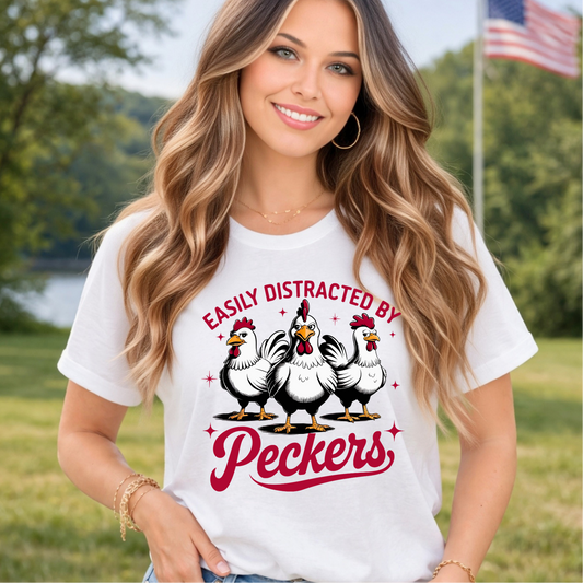 Woman wearing a white t-shirt with a graphic of chickens and text in an outdoor setting.