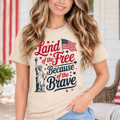 Woman wearing a t-shirt with 'Land of the Free Because of the Brave' design, standing outdoors.