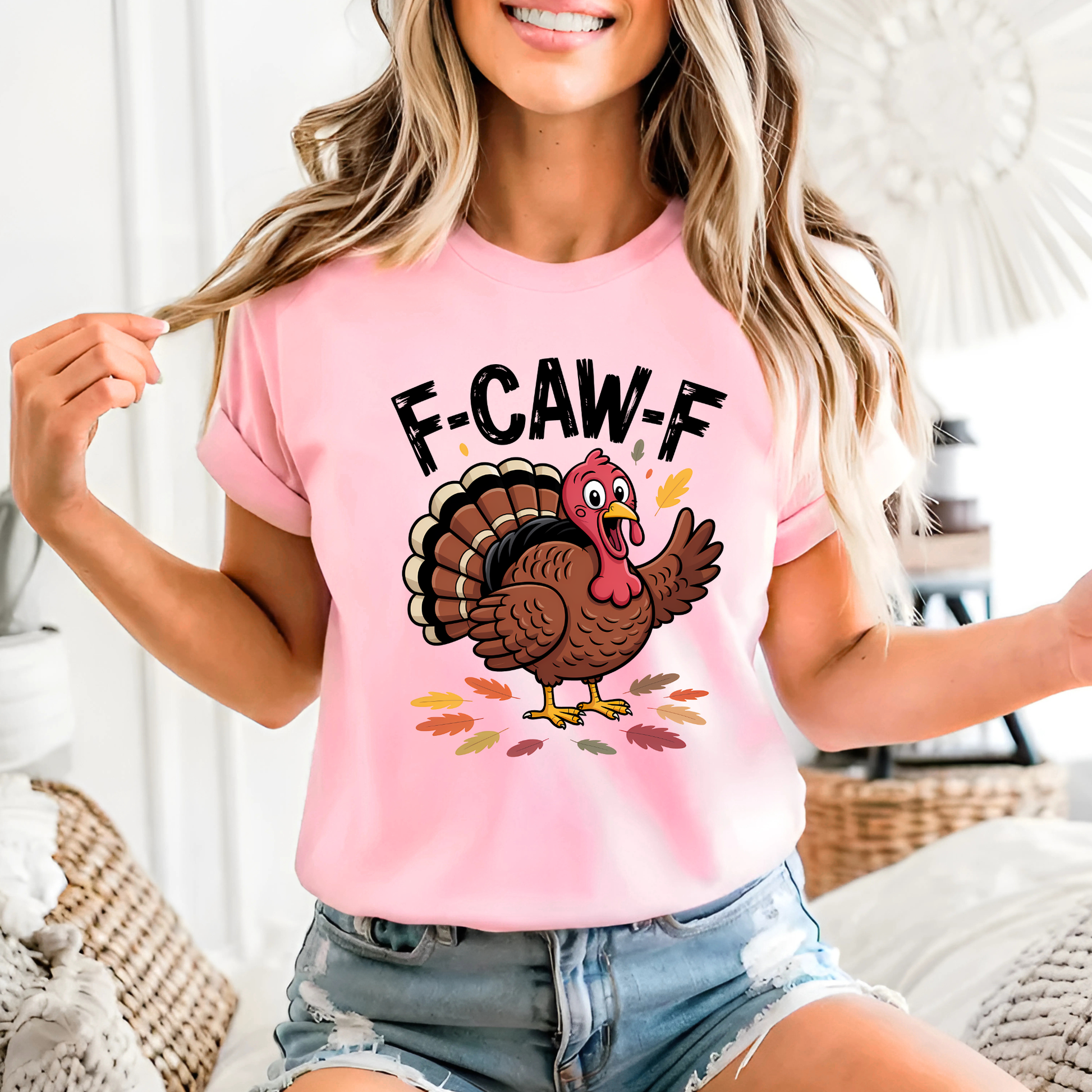 Woman wearing light pink “F-CAW-F” turkey shirt with cartoon turkey and fall leaves