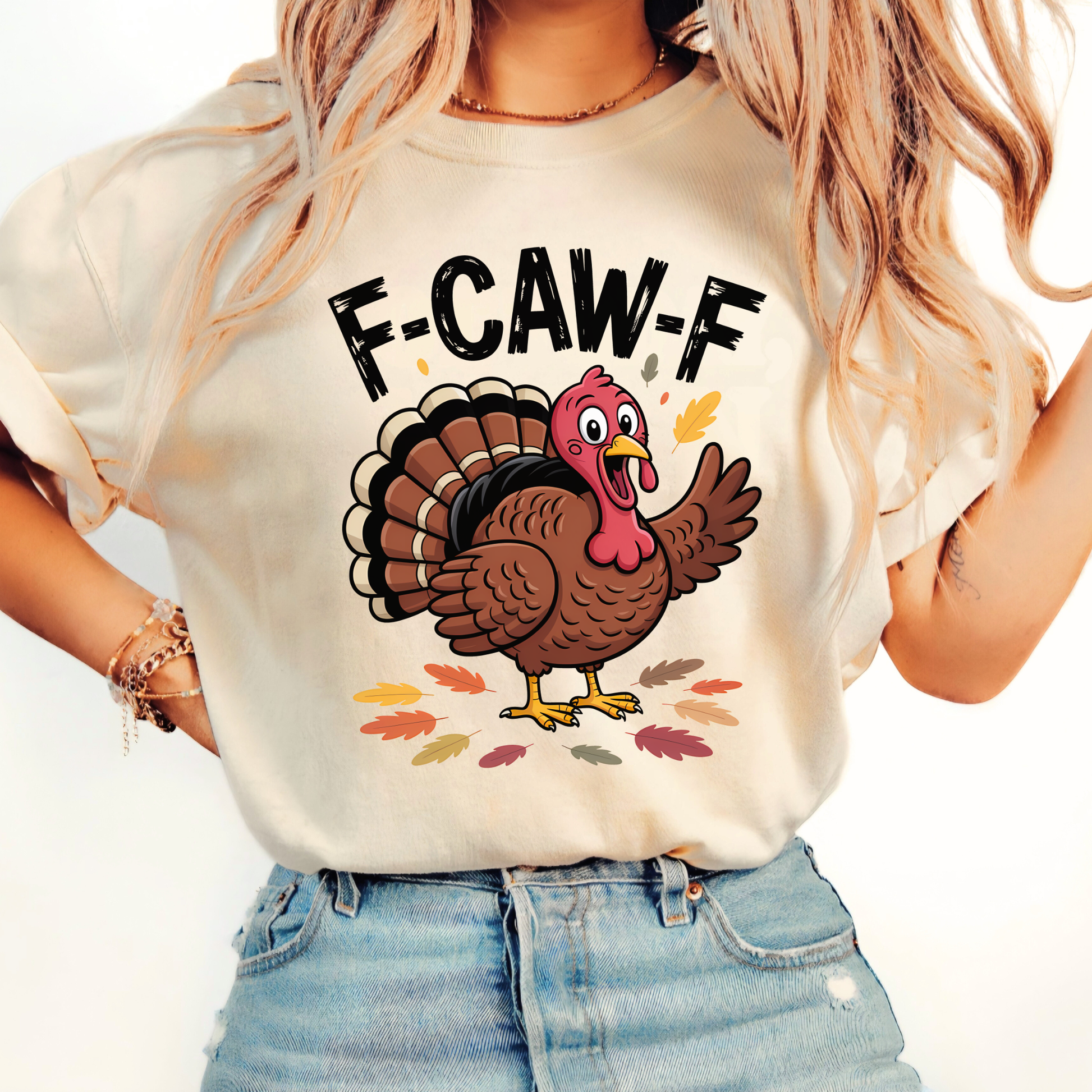 Woman wearing sand “F-CAW-F” turkey shirt with fall leaf design and rolled sleeves