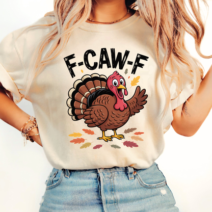 Woman wearing sand “F-CAW-F” turkey shirt with fall leaf design and rolled sleeves