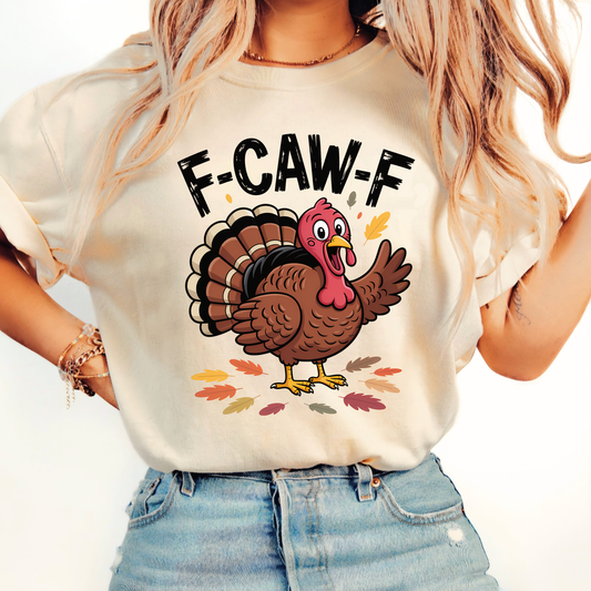 Woman wearing sand “F-CAW-F” turkey shirt with fall leaf design and rolled sleeves