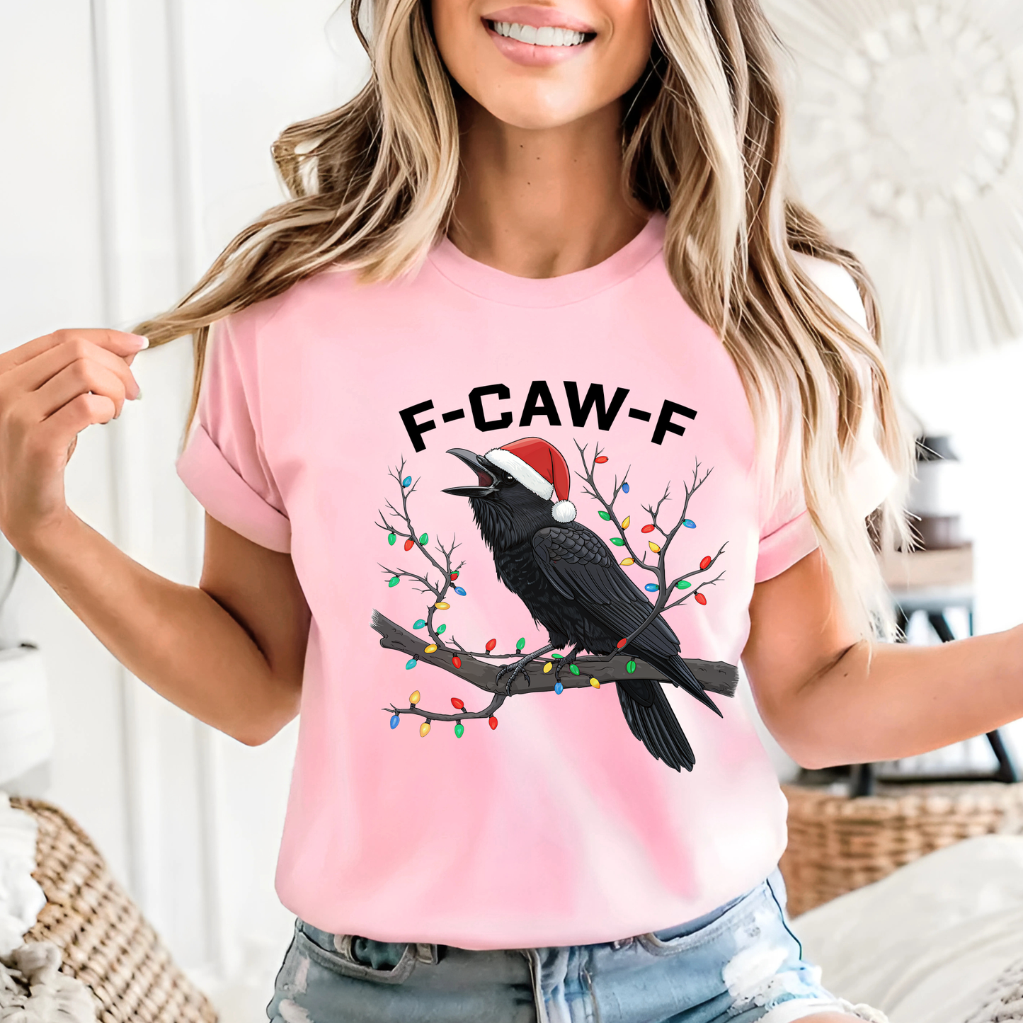 Woman wearing light pink crow holiday shirt with festive branch design.