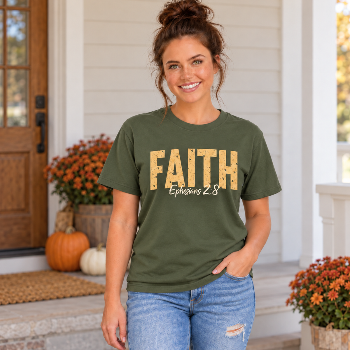 Woman wearing a military green T-shirt with distressed gold FAITH lettering and white Ephesians 2:8 script in an autumn porch setting.