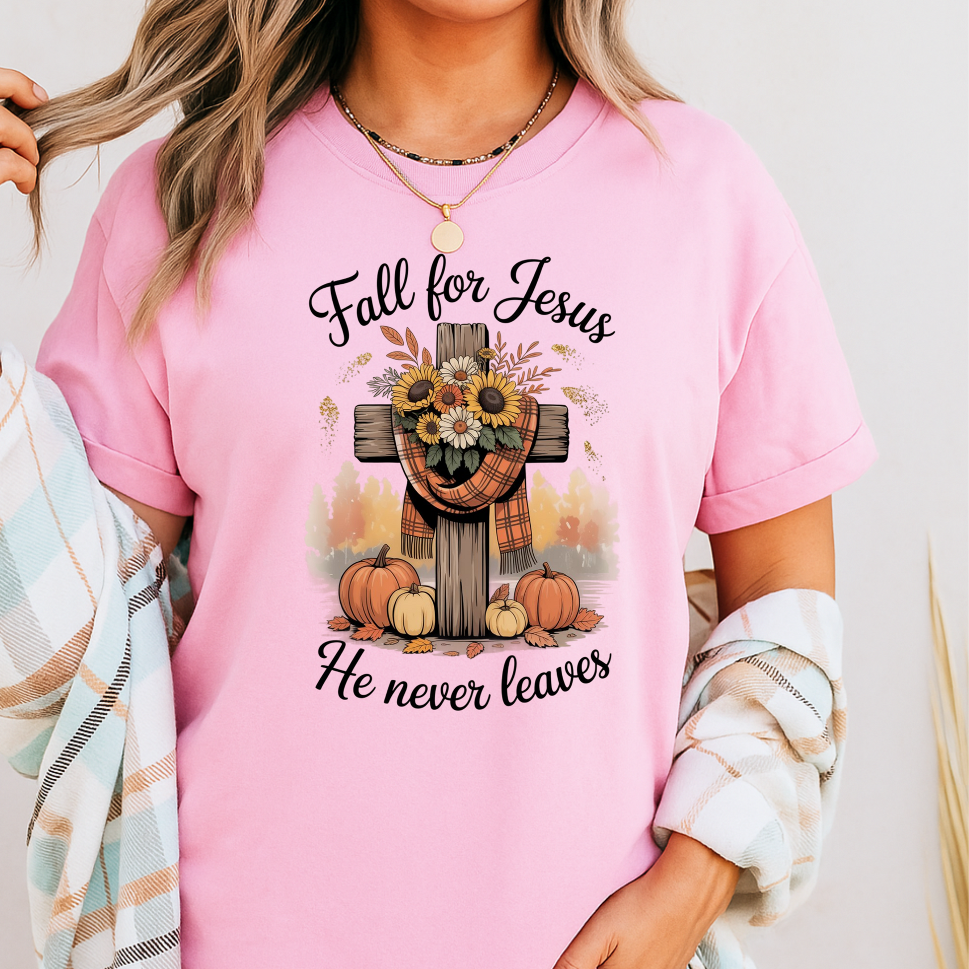 Person wearing a pink t-shirt with 'Fall for Jesus He never leaves' design.