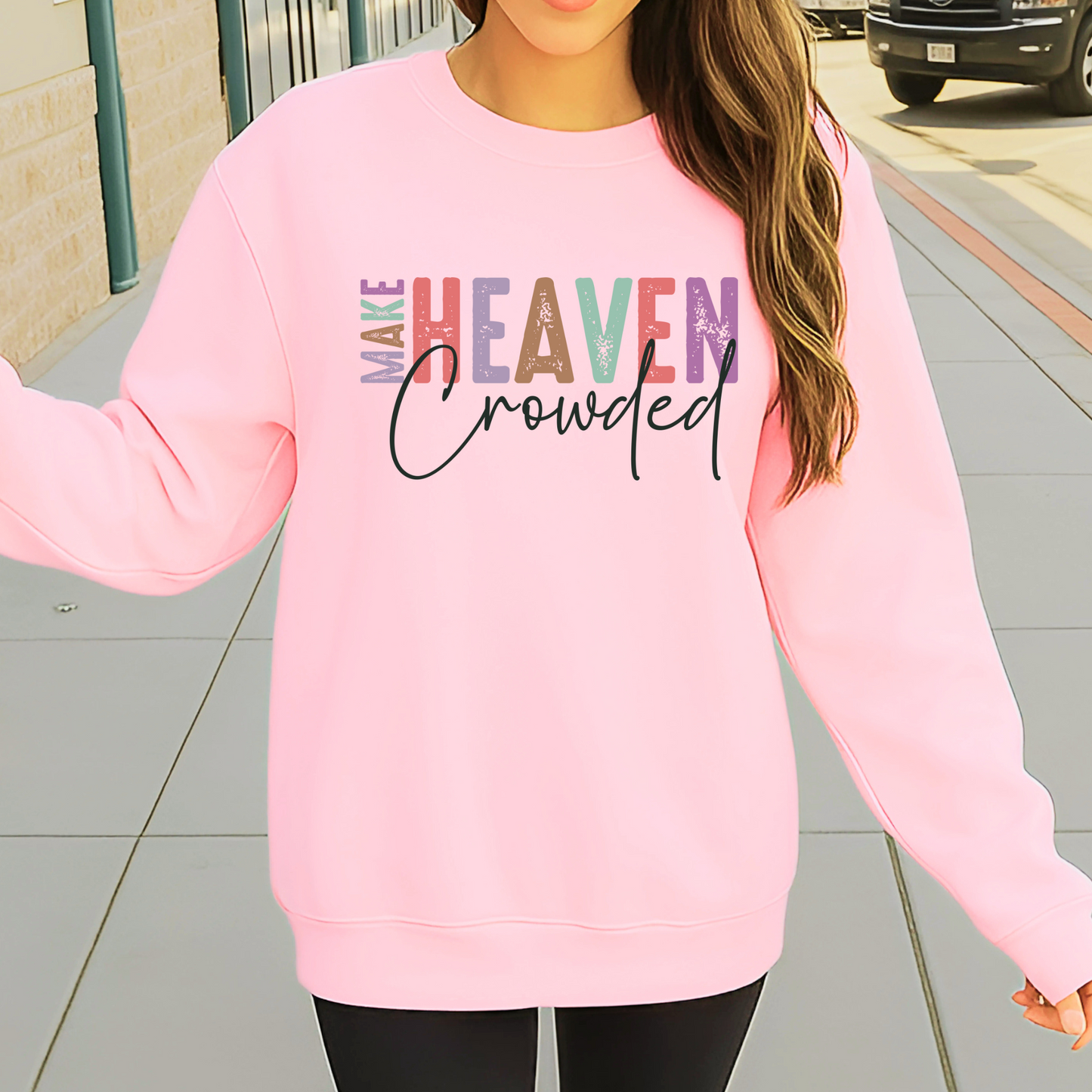 Person wearing a pink sweatshirt with colorful text on a sidewalk.