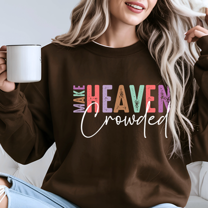 Woman wearing brown Christian sweatshirt with bold multicolor “Make Heaven Crowded” design, holding coffee mug. Religious inspirational faith crewneck for women.