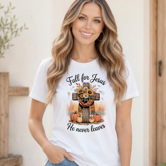 Woman wearing a white T-shirt with the Fall for Jesus He Never Leaves design featuring a cross, pumpkins, and sunflowers.