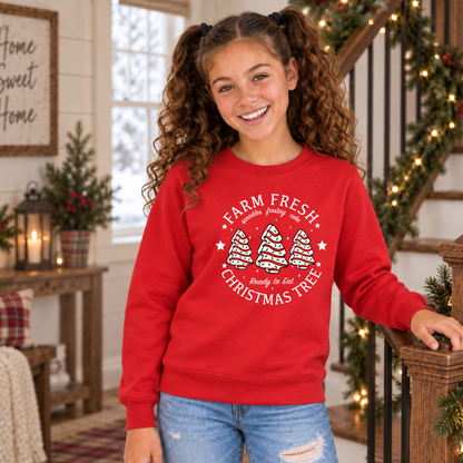 Girl wearing a red Farm Fresh Christmas Tree Cakes sweatshirt beside a decorated stair railing.