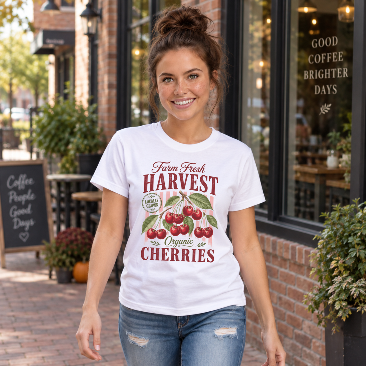 Woman walking past a coffee shop in a white Farm Fresh Harvest Organic Cherries T-shirt with red cherry graphic.