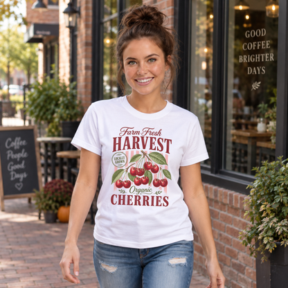 Woman walking past a coffee shop in a white Farm Fresh Harvest Organic Cherries T-shirt with red cherry graphic.