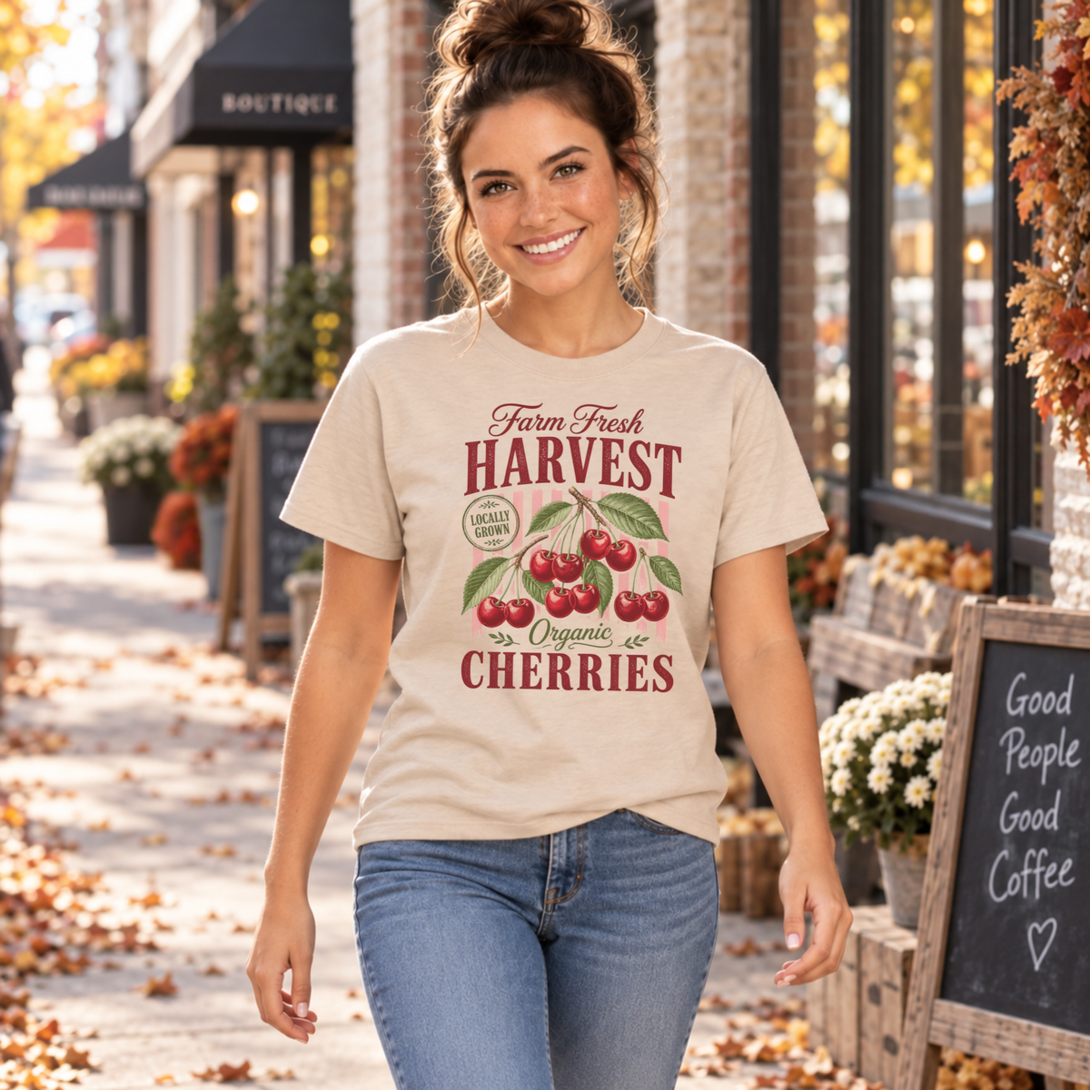 Woman walking along a storefront in a sand Farm Fresh Harvest Organic Cherries T-shirt.