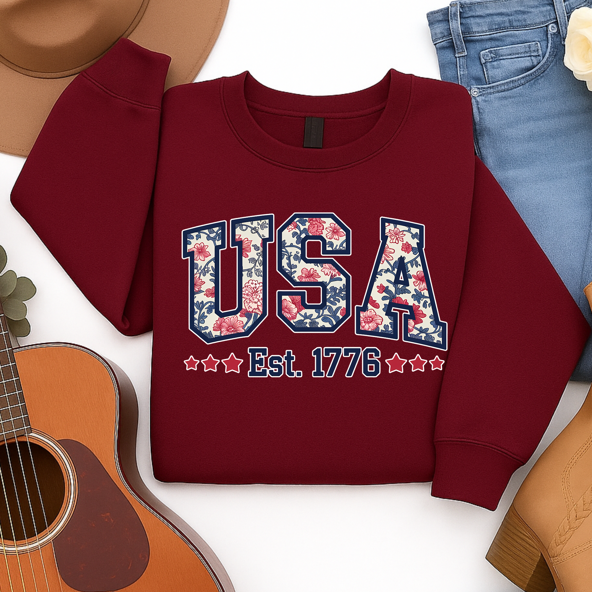 Flat lay of maroon USA Est. 1776 youth sweatshirt with patriotic floral print.


