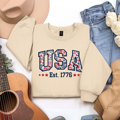 Sand beige floral USA sweatshirt – styled flat lay with jeans and western accessories.

