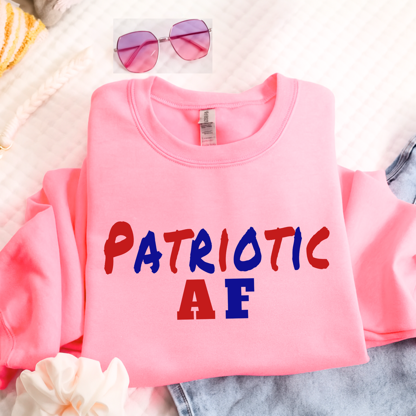 Folded Pink patriotic AF sweatshirt flat lay with accessories